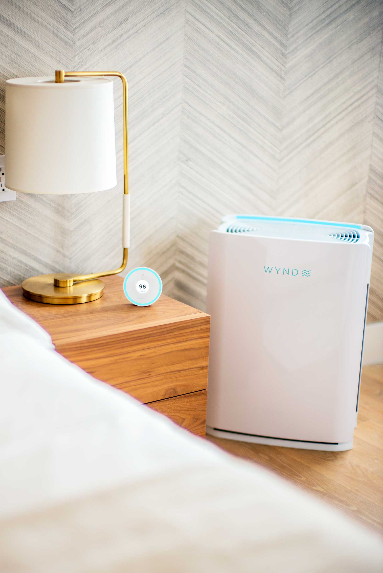Photo of the Wynd Halo and Wynd Home Purifier next to a nightstand in a bedroom